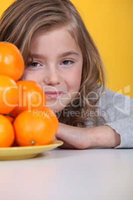 Girl hiding behind a plate of clementines