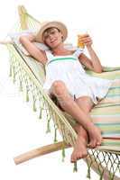blonde woman resting and drinking in a hammock