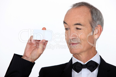 senior in a suit holding a business card
