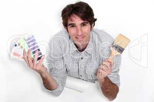 Man holding colour samples and a paintbrush