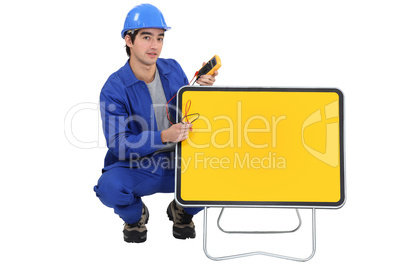 Tradesman squatting next to a traffic sign