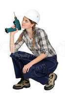 Handywoman crouching with drill