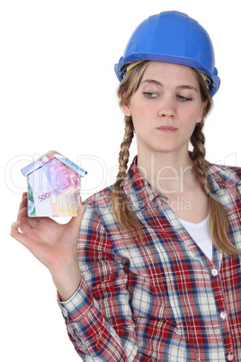 craftswoman holding a little model of house made of banknotes