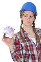 craftswoman holding a little model of house made of banknotes