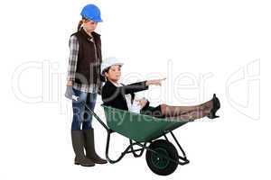 Woman laborer and businesswoman in a wheelbarrow