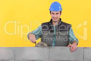 Mason spreading cement on wall with trowel