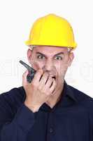 angry businessman wearing helmet and shouting on a walkie talkie