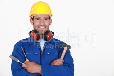 portrait of craftsman with safety helmet and earmuffs holding tools