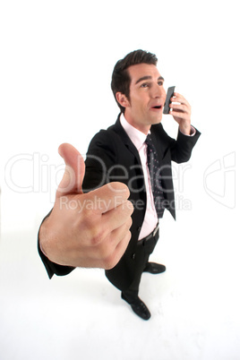 Businessman talking on his mobile phone and giving the thumb's up