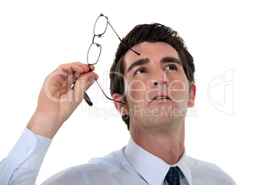 Man taking his glasses off and looking upwards