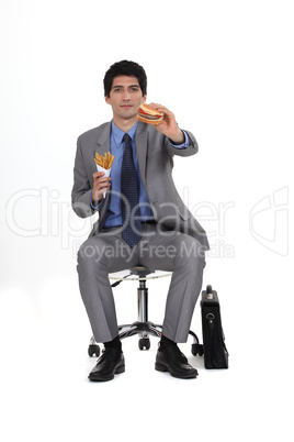 Businessman sat eating burger and fries