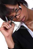 Businesswoman with pen lifting glasses frame