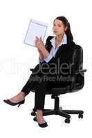 Woman sitting on chair pointing at clipboard