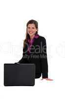 Businesswoman sitting on an invisible bench with her laptop