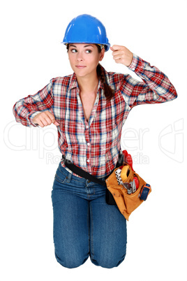Young woman laborer gesturing, kneeling on white background