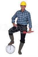 Happy laborer leaning on a clock, studio shot