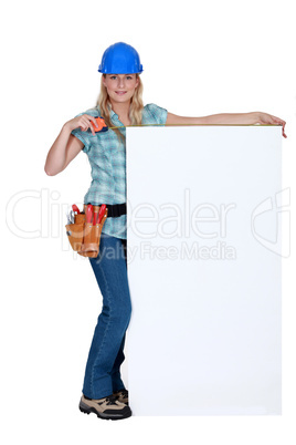 Tradeswoman standing next to a blank sign
