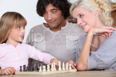 Parents and daughter playing chess