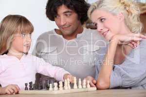 Parents and daughter playing chess