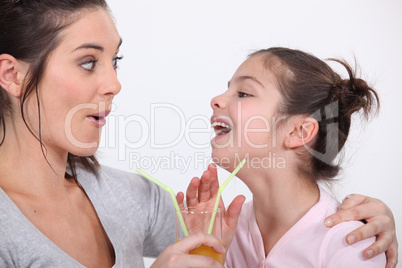 Mother and daughter drinking from the same glass