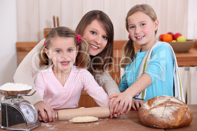 Mother rolling dough with two daughters