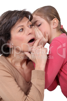 little girl telling a secret to her mother