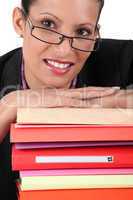 Smiling woman leaning on a stack of books