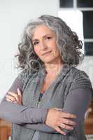 Grey haired woman stood in the kitchen with her arms folded