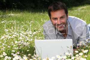 Man working on laptop in the daisies