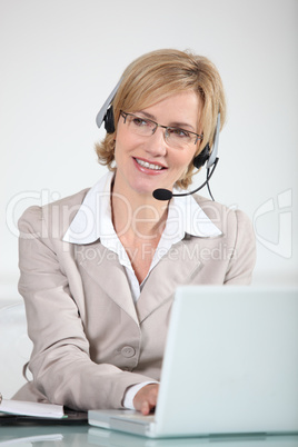 Woman using a telephone headset at a laptop computer