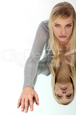 portrait of cute blonde looking depressed reflected on glass table