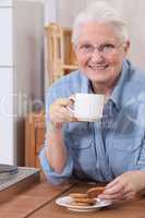 Elderly woman eating biscuits and drinking tea