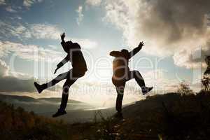 Happy young woman and man jumping at the sunset