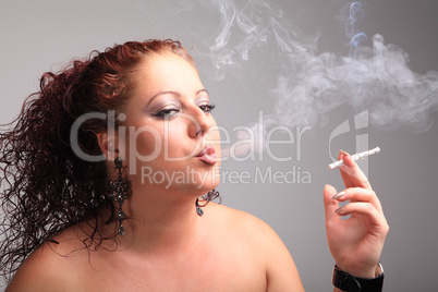 Young beautiful girl smokes a cigarette, produces smoke