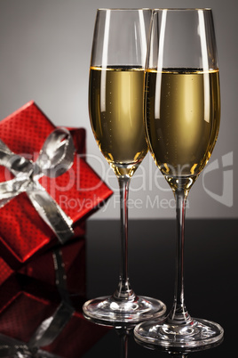zwei gläser mit champagner vor rotem geschenk