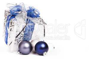 silbernes weihnachtsgeschenk mit blauen schleifen und christbaumkugeln