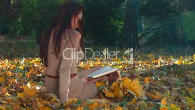 Young Woman Reading a Book in Autumn Park
