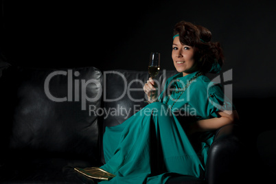 Beautiful girl sitting on a sofa with glass of wine