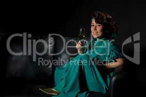 Beautiful girl sitting on a sofa with glass of wine