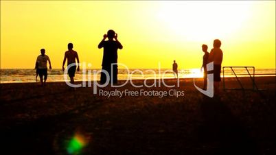 silhouette of football players on the beach at sunset