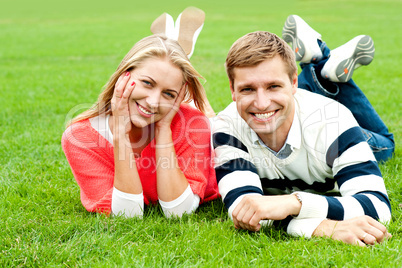 Charming young couple lying on green grass