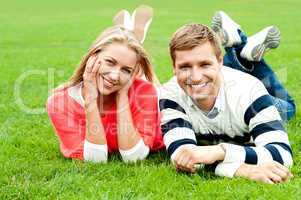 Charming young couple lying on green grass