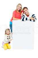 Portrait of happy family presenting blank whiteboard