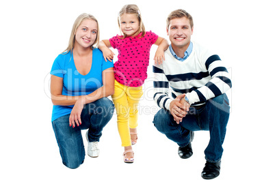 Trendy couple squatting with girl child in between