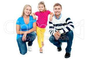 Trendy couple squatting with girl child in between