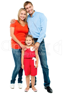 Mother, father and cute daughter posing in trendy outfits