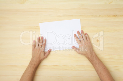 male's hand holds a blank paper