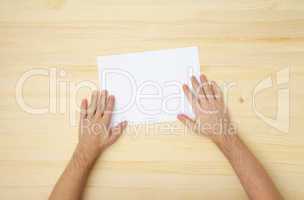 male's hand holds a blank paper