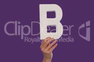 Female hand holding up the letter B from the bottom