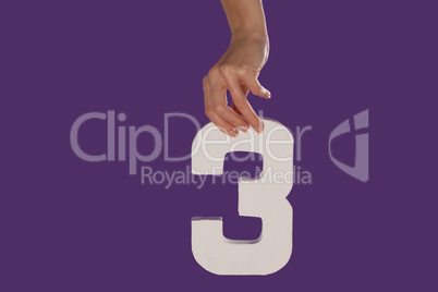 Female hand holding up the number 3  from the top